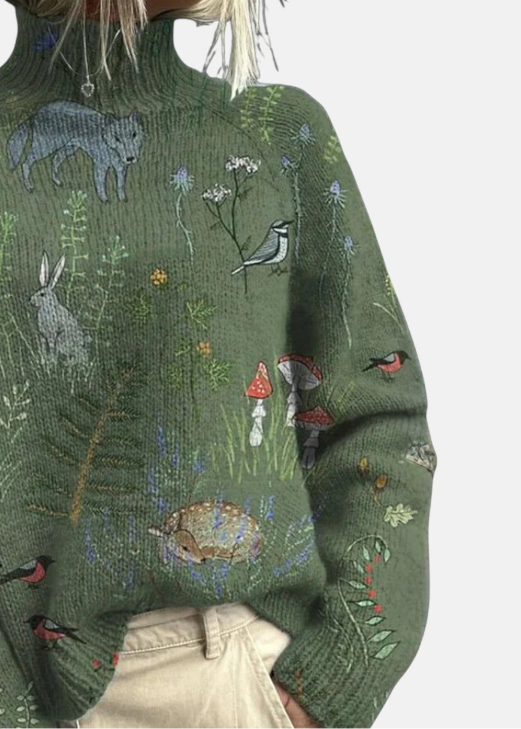 Close-up green turtleneck sweater with embroidered rabbits, birds, and mushrooms