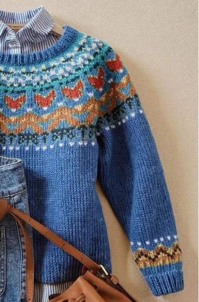 Blue knit jumper side view with colorful yoke motif and ribbed cuffs