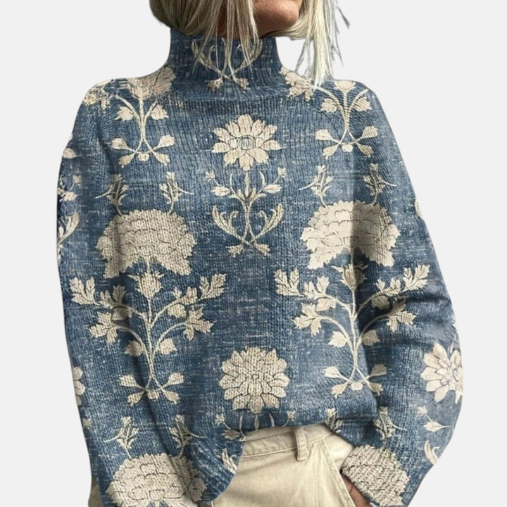 Close-up blue turtleneck jumper with cream floral motifs and ribbed neckline
