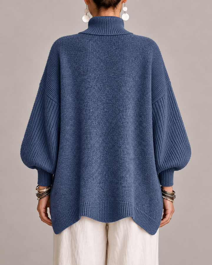 Back view of blue turtleneck knit sweater with ribbed cuffed dolman sleeves.
