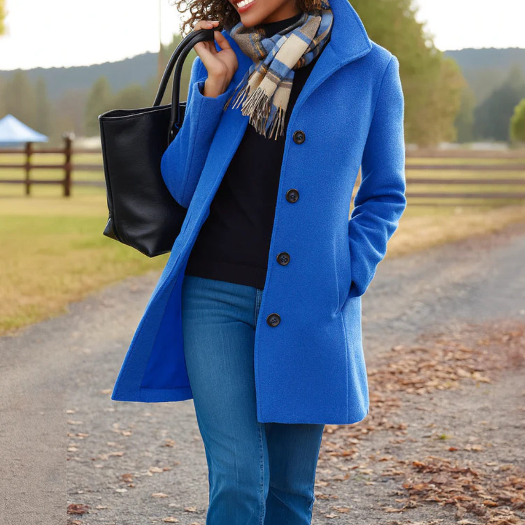 Blue long coat with dark buttons and notch lapels, styled with scarf and jeans