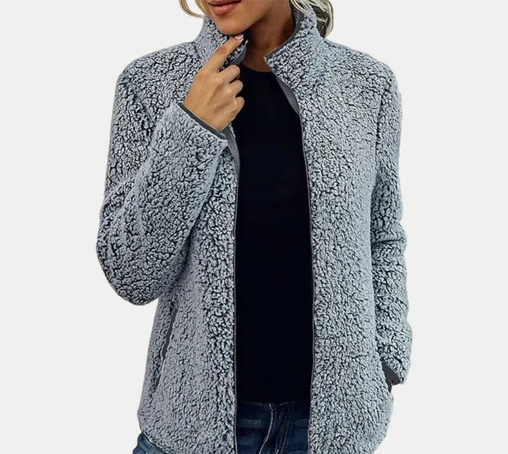 Grey teddy jacket worn open over dark top, long sleeves and full zipper