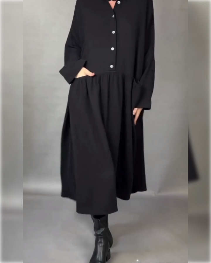 Black button-front A-line dress with point collar and long sleeves, gathered skirt.