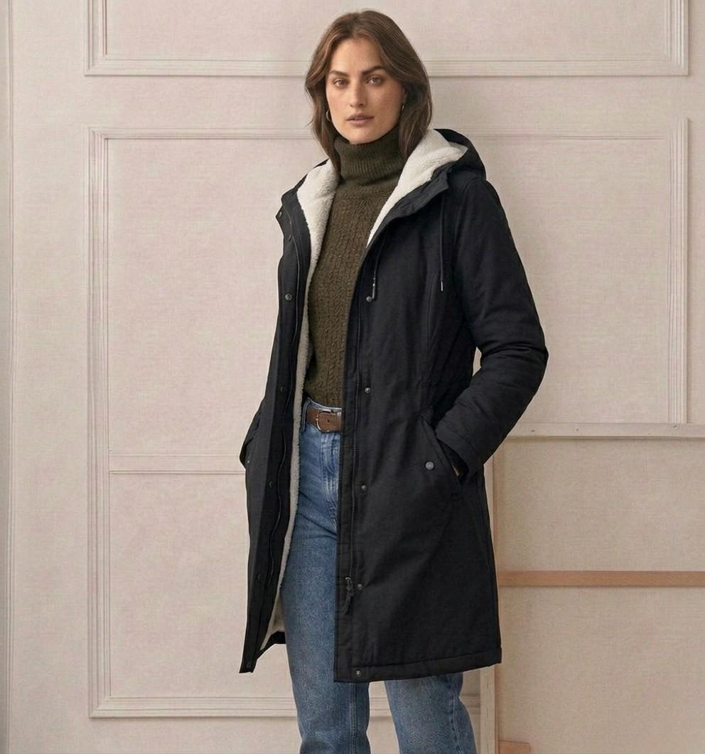 Dark waterproof long parka on model with sherpa-lined hood and front zipper