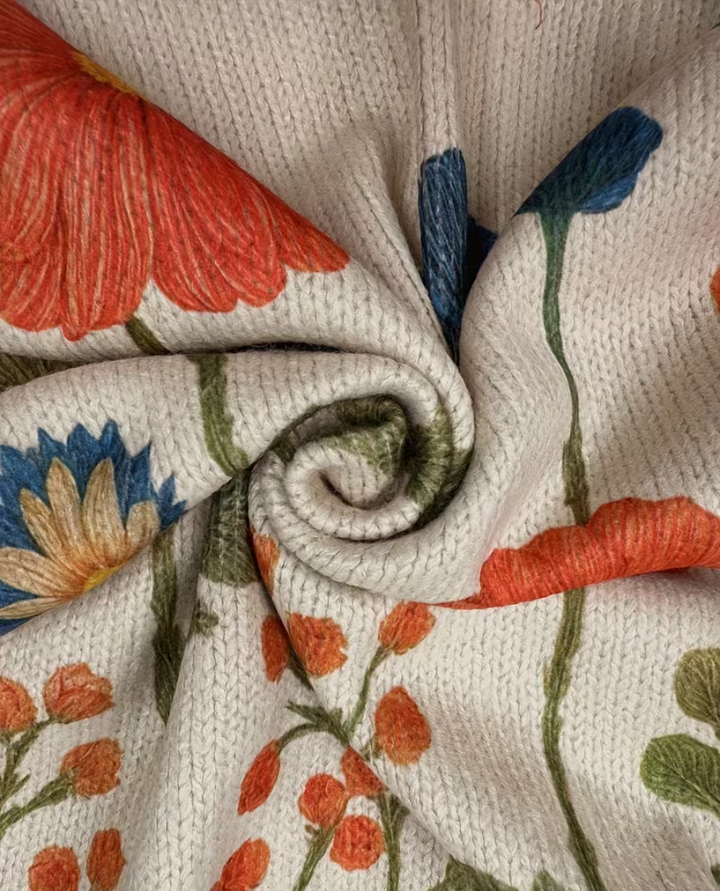 Floral knit cardigan close-up, cream texture with orange blossoms and blue stems