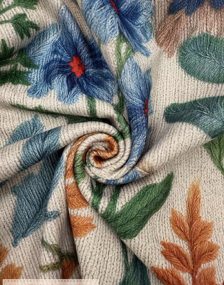 Close-up knit fabric of cream cardigan with blue flowers and green leaf pattern