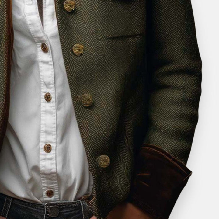 Close-up of olive herringbone military jacket with brass buttons and flap pocket
