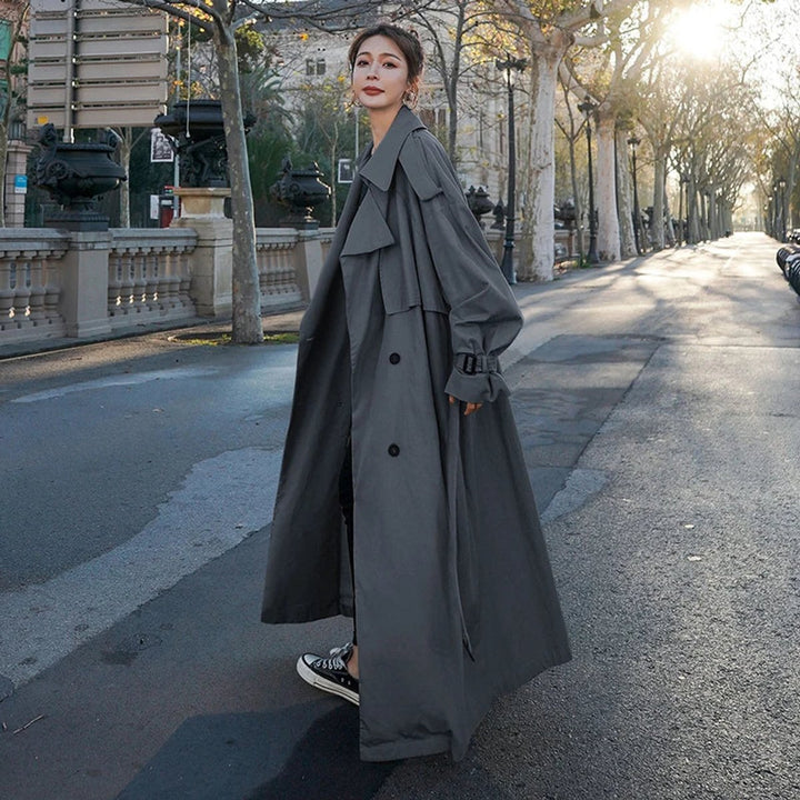 Dark gray long trench coat with double-breasted front, notched collar, and waist tie