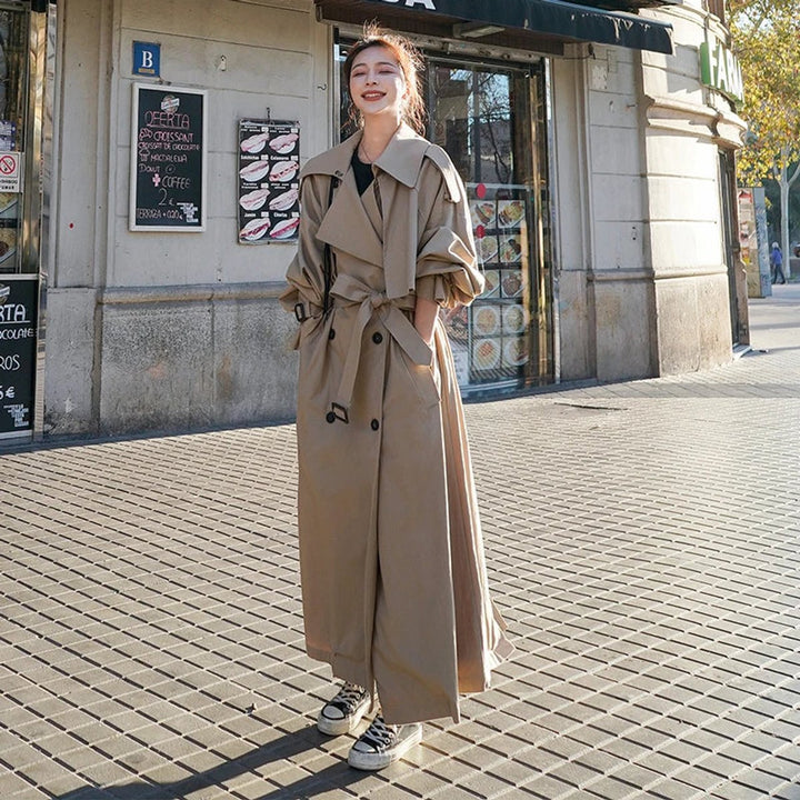Khaki long trench coat with double-breasted buttons, notched collar, and waist belt